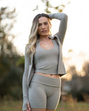 Woman in athletic wear standing outdoors with a blurred natural background