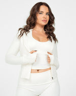 Woman wearing a white outfit against a plain background