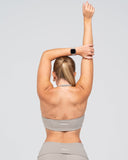 Person wearing a gray sports bra and leggings with a plain background