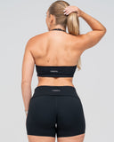 Person wearing a black sports bra and shorts set with 'Venova' branding on a gray background