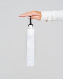 Hand holding a white keychain with a logo against a gray background