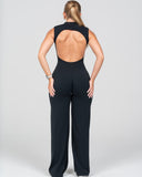 Person wearing a black open-back jumpsuit on a plain background